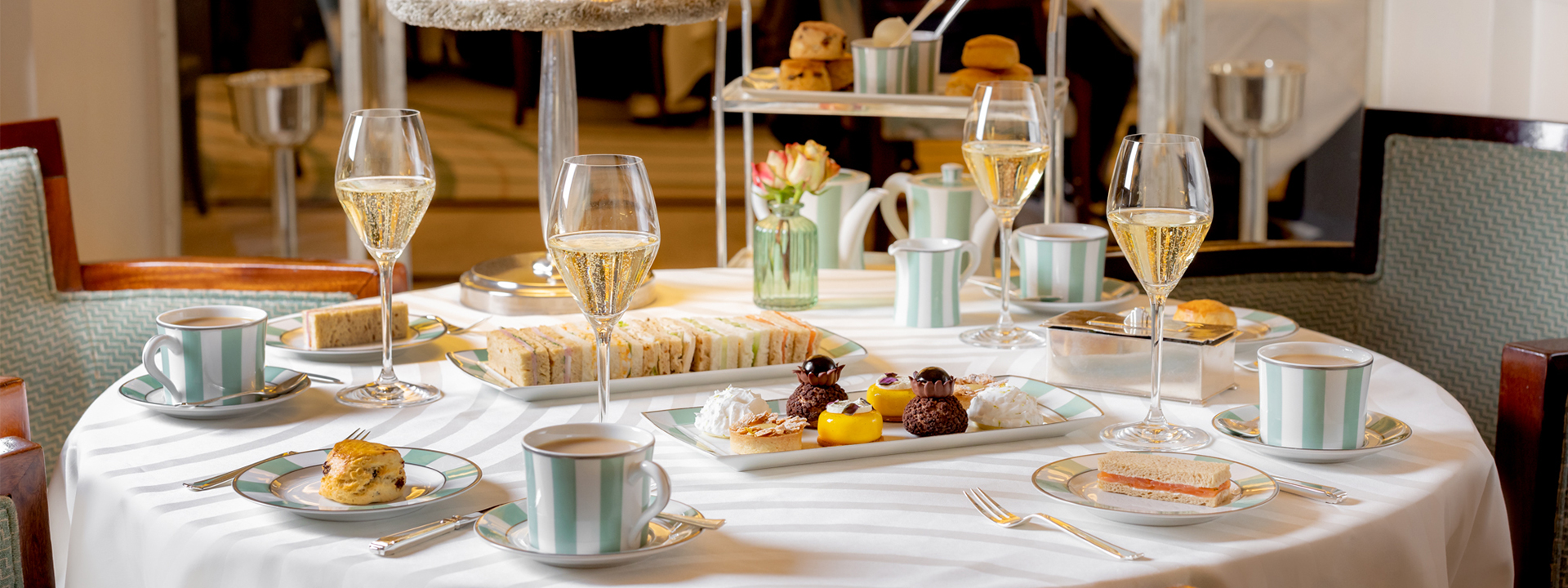 A selection of cakes and finger sandwiches with champagne glasses at The Foyer and Reading Room.