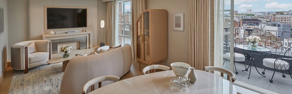 Living area and dining area of Claridge's Terrace Suite with beige furniture and open doors to terrace