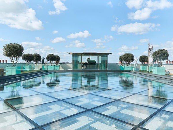 Rooftop glass water feature leading to glass pavilion with grand piano inside